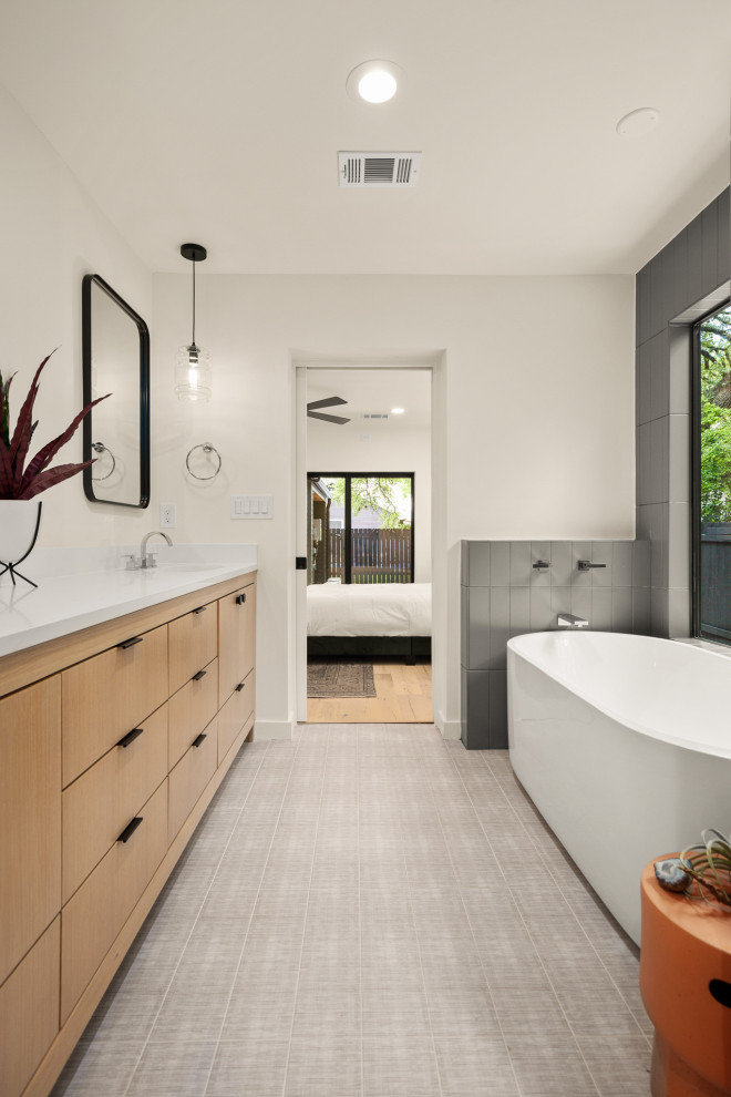 Inspiration for a contemporary gray floor freestanding bathtub remodel in Austin with flat-panel cabinets, medium tone wood cabinets, white walls, an undermount sink, white countertops and a built-in vanity