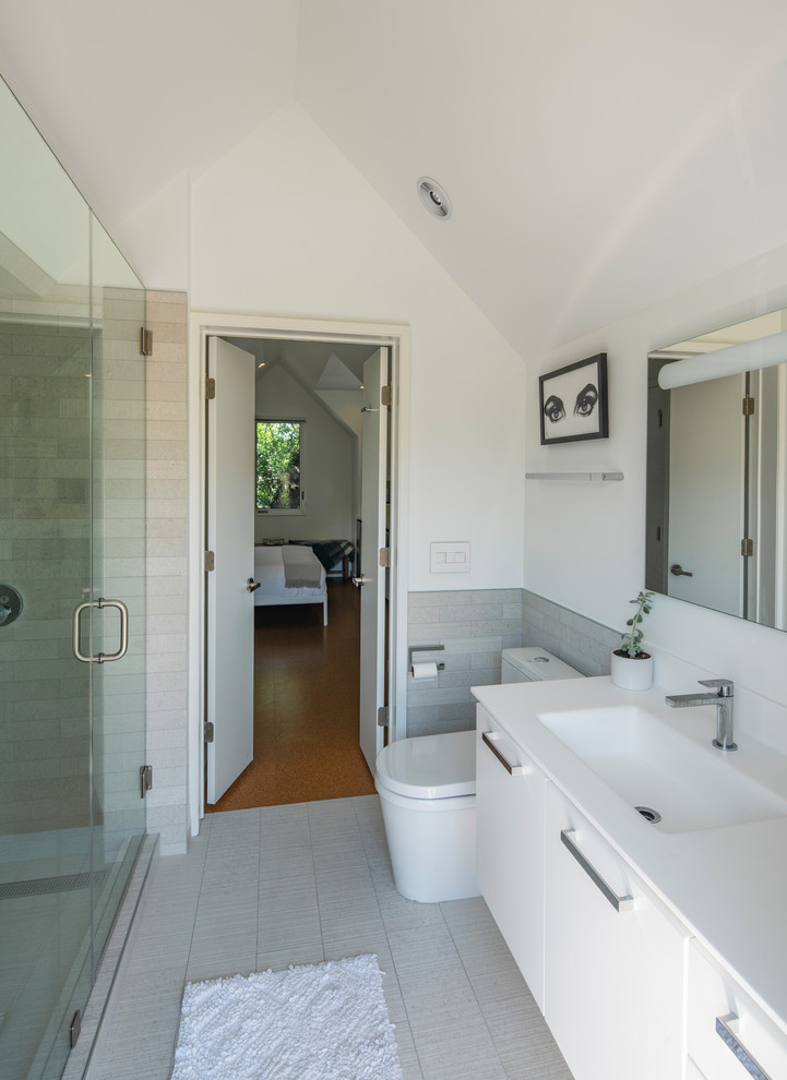 Inspiration for a small modern master gray tile and porcelain tile porcelain tile and gray floor alcove shower remodel in Austin with flat-panel cabinets, white cabinets, a two-piece toilet, white walls, an integrated sink, solid surface countertops, a hinged shower door and white countertops