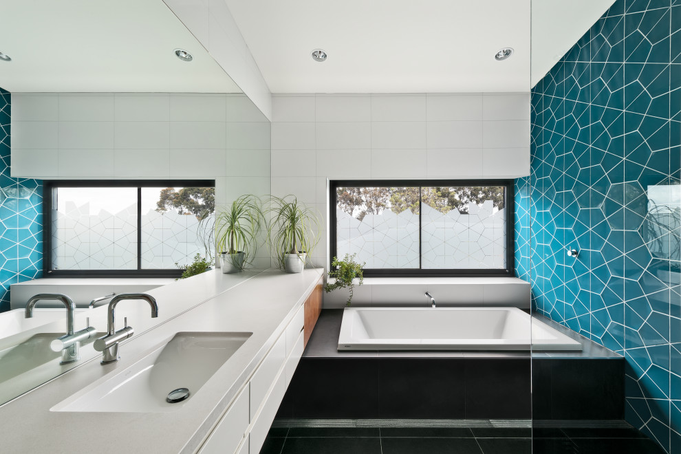 Ispirazione per un'ampia stanza da bagno design con ante lisce, ante bianche, vasca da incasso, piastrelle blu, lavabo sottopiano, top bianco e mobile bagno sospeso