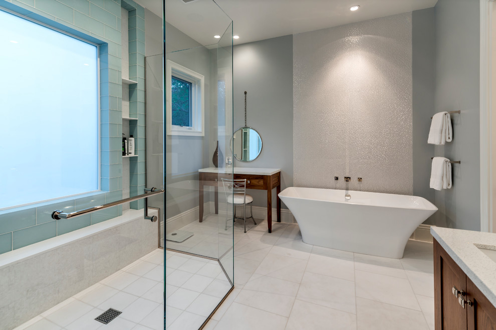 Imagen de cuarto de baño contemporáneo con armarios estilo shaker, puertas de armario de madera en tonos medios, bañera exenta, paredes grises y lavabo bajoencimera