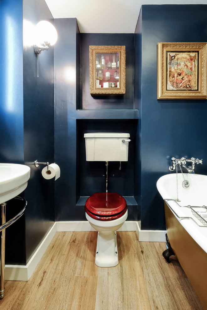 Kleines Eklektisches Kinderbad mit verzierten Schränken, hellbraunen Holzschränken, Löwenfuß-Badewanne, Wandtoilette mit Spülkasten, blauer Wandfarbe, hellem Holzboden und Sockelwaschbecken in Sussex