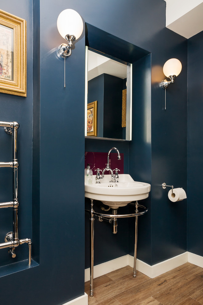 Example of a small eclectic kids' light wood floor claw-foot bathtub design in Sussex with furniture-like cabinets, medium tone wood cabinets, a two-piece toilet, blue walls and a pedestal sink