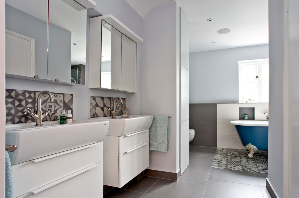 Large minimalist master gray tile and porcelain tile porcelain tile bathroom photo in Oxfordshire with an integrated sink, flat-panel cabinets, white cabinets, a wall-mount toilet and blue walls