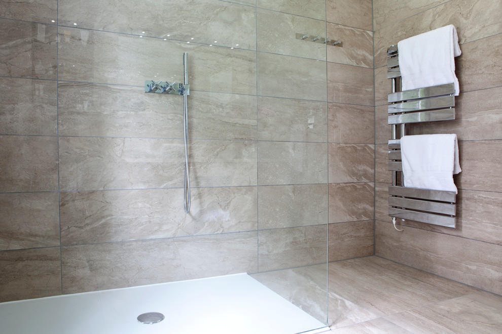 This is an example of a medium sized contemporary ensuite bathroom in Sussex with recessed-panel cabinets, light wood cabinets, a walk-in shower, a one-piece toilet, beige tiles, stone tiles, beige walls, marble flooring, a console sink and engineered stone worktops.