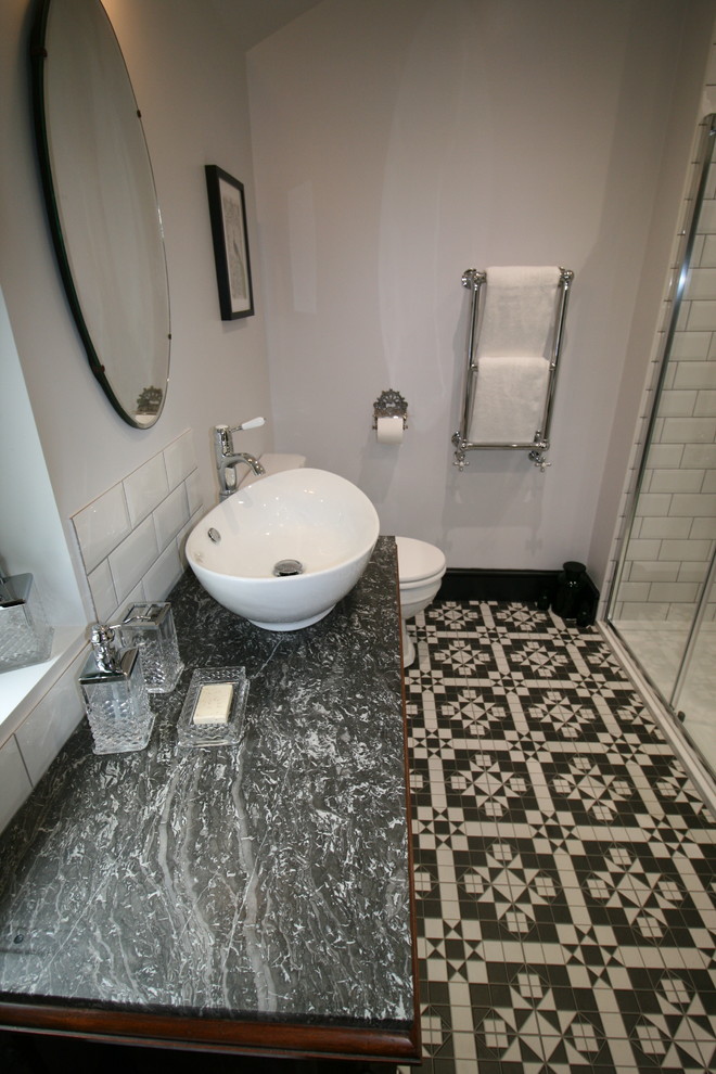 This is an example of a medium sized victorian bathroom in Other with beaded cabinets, dark wood cabinets, a freestanding bath, a corner shower, a two-piece toilet, black and white tiles, porcelain tiles, grey walls, porcelain flooring, a trough sink and marble worktops.