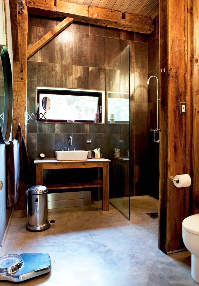 Inredning av ett rustikt mellanstort badrum, med ett fristående handfat, porslinskakel, betonggolv, öppna hyllor, skåp i mellenmörkt trä, en dusch i en alkov, bruna väggar, brunt golv och dusch med gångjärnsdörr