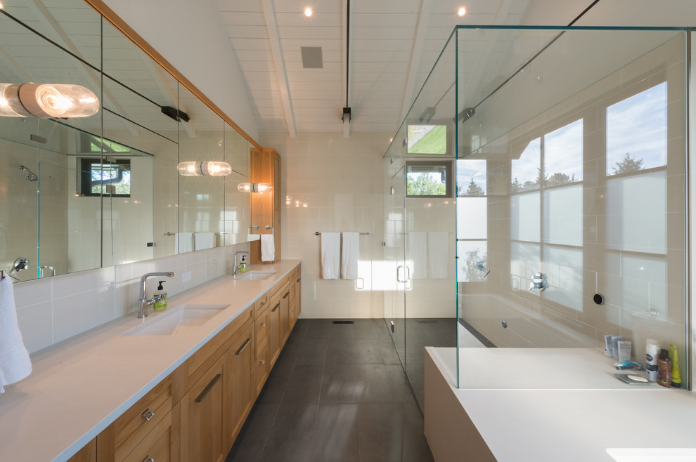 Exemple d'une salle de bain principale moderne en bois clair de taille moyenne avec un placard à porte shaker, une baignoire indépendante, une douche d'angle, un carrelage blanc, des carreaux de céramique, un mur blanc, un sol en ardoise, un lavabo encastré et un plan de toilette en surface solide.