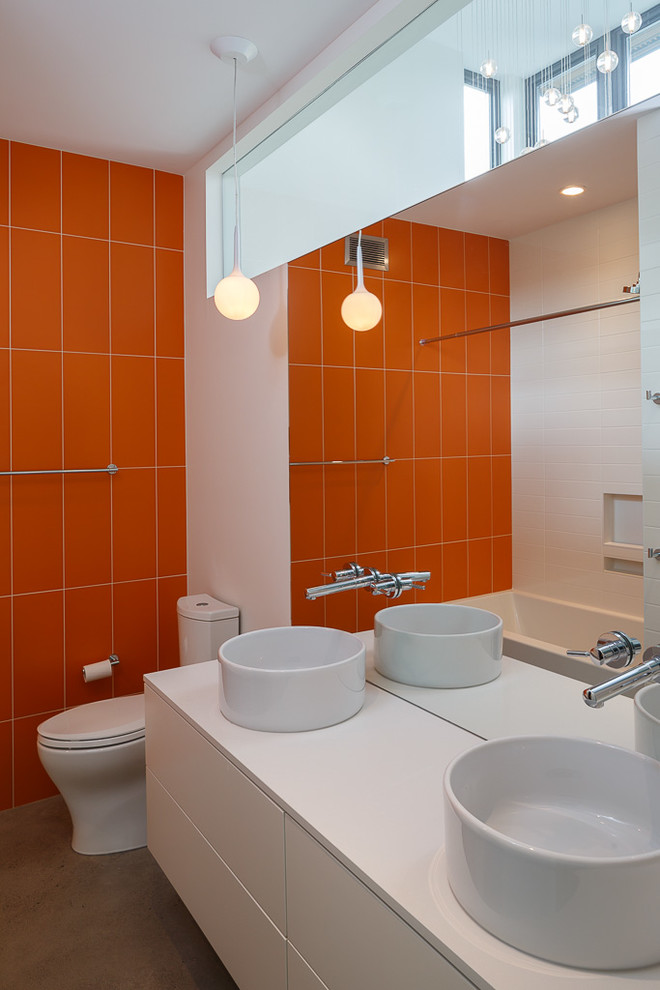 Inspiration for a contemporary bathroom in Ottawa with a vessel sink, flat-panel cabinets, white cabinets, an alcove bath, a shower/bath combination, orange tiles, white walls and concrete flooring.