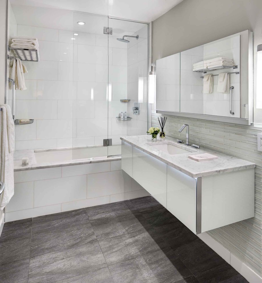 Inspiration for a contemporary white tile gray floor tub/shower combo remodel in New York with an undermount sink, flat-panel cabinets, white cabinets, an undermount tub and gray walls