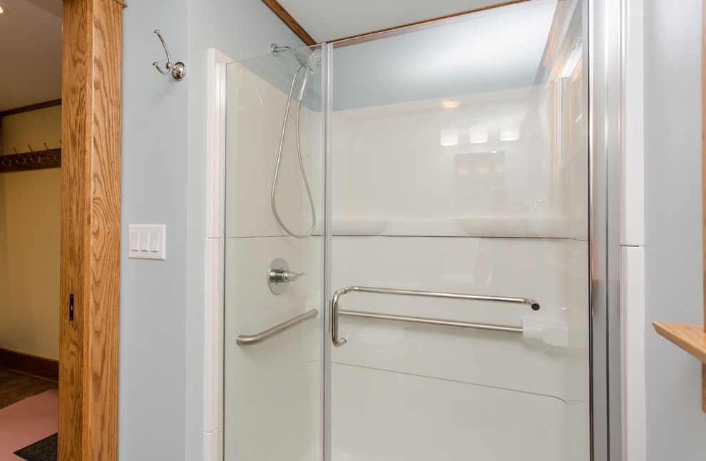 Exempel på ett litet amerikanskt badrum med dusch, med en dusch i en alkov, en toalettstol med separat cisternkåpa, blå väggar, vinylgolv, ett piedestal handfat, flerfärgat golv och dusch med gångjärnsdörr