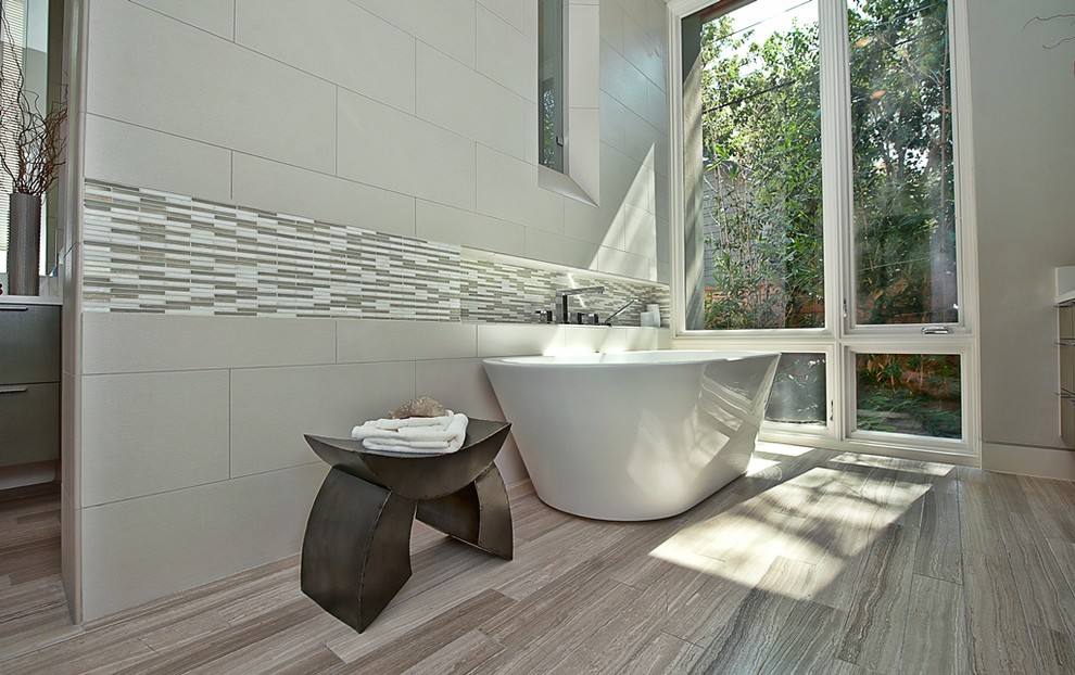 Пример оригинального дизайна: ванная комната в современном стиле с отдельно стоящей ванной и белой плиткой