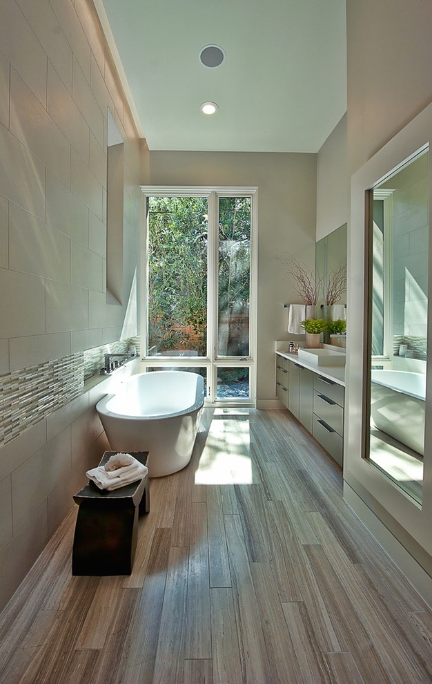 Trendy beige tile and stone tile freestanding bathtub photo in Austin with a vessel sink