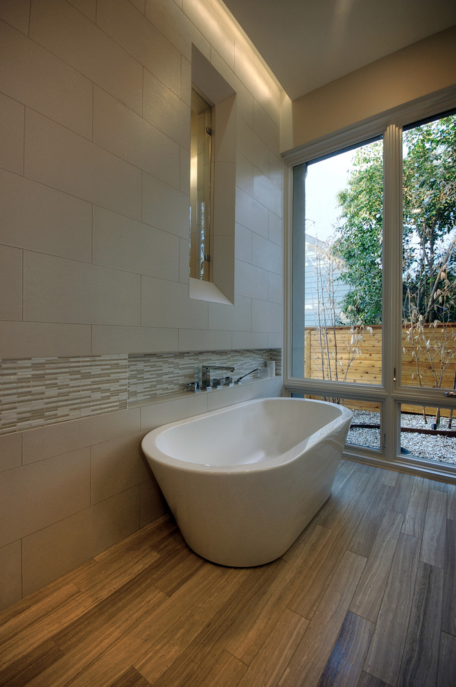 Example of a trendy travertine tile freestanding bathtub design in Austin with a niche