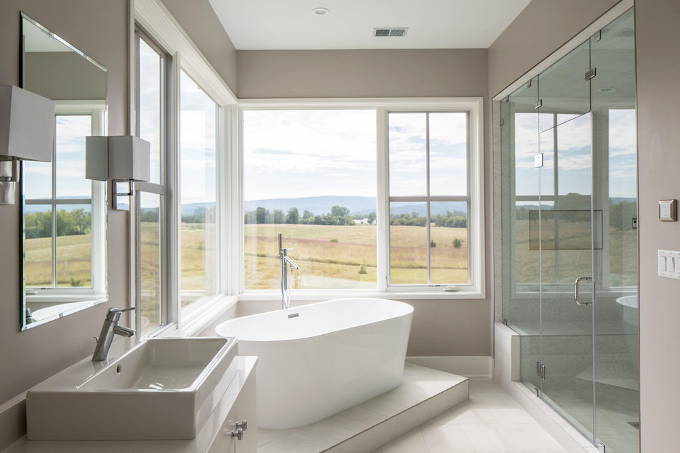 Cette image montre une salle de bain minimaliste avec une vasque, un placard à porte plane, des portes de placard blanches, un plan de toilette en quartz modifié, une baignoire indépendante, un carrelage gris, des carreaux de porcelaine et un sol en carrelage de porcelaine.