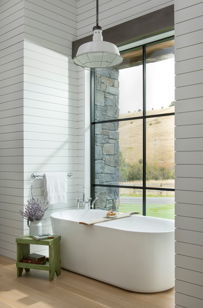 Ispirazione per un'ampia stanza da bagno padronale country con vasca freestanding, pareti bianche e parquet chiaro