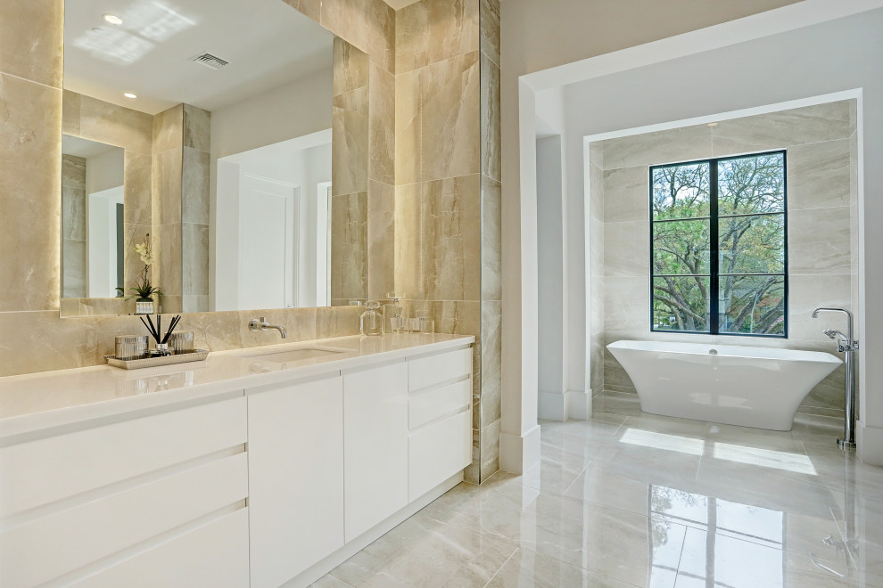 Großes Modernes Badezimmer En Suite mit flächenbündigen Schrankfronten, weißen Schränken, freistehender Badewanne, beigen Fliesen, weißer Wandfarbe, Unterbauwaschbecken, beigem Boden, weißer Waschtischplatte, Doppelwaschbecken und eingebautem Waschtisch in Houston