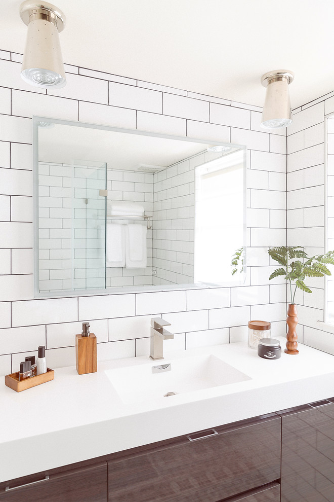 Small retro shower room bathroom in Houston with freestanding cabinets, grey cabinets, an alcove shower, a two-piece toilet, white tiles, ceramic tiles, white walls, ceramic flooring, an integrated sink, solid surface worktops, multi-coloured floors, a hinged door and white worktops.