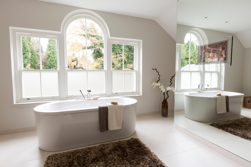 На фото: ванная комната в современном стиле с отдельно стоящей ванной и бежевыми стенами с