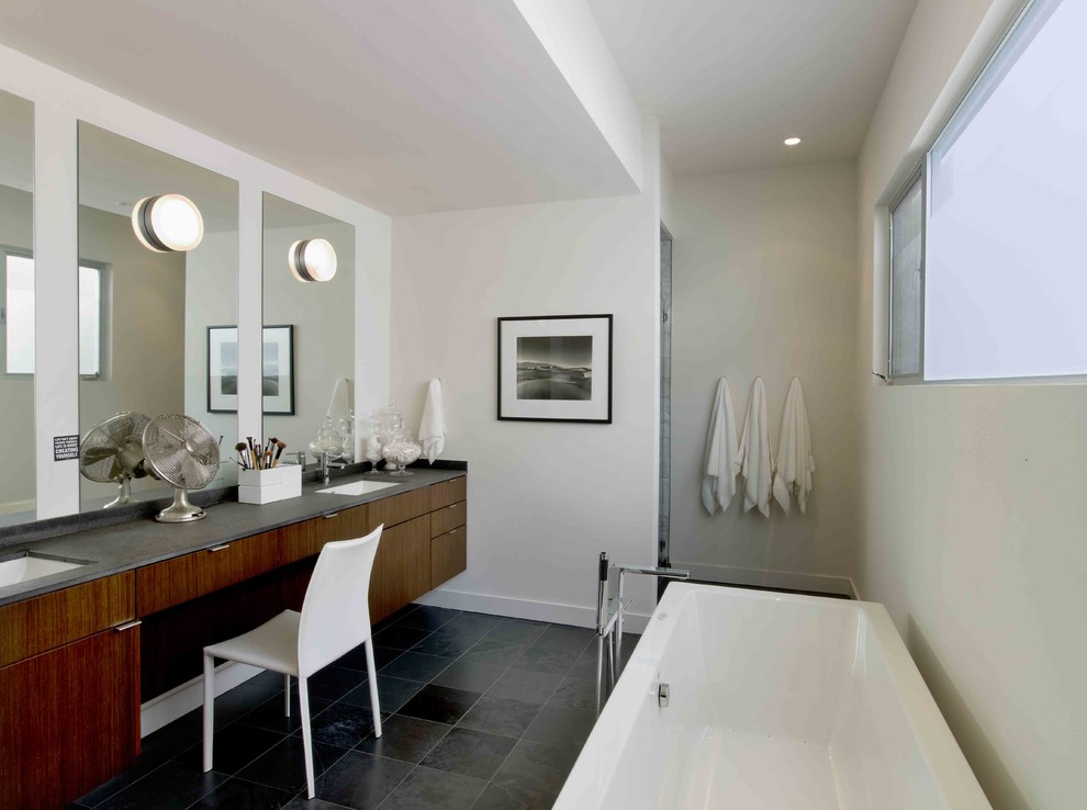Exempel på ett modernt badrum, med ett undermonterad handfat, släta luckor, skåp i mörkt trä, ett fristående badkar och grå kakel