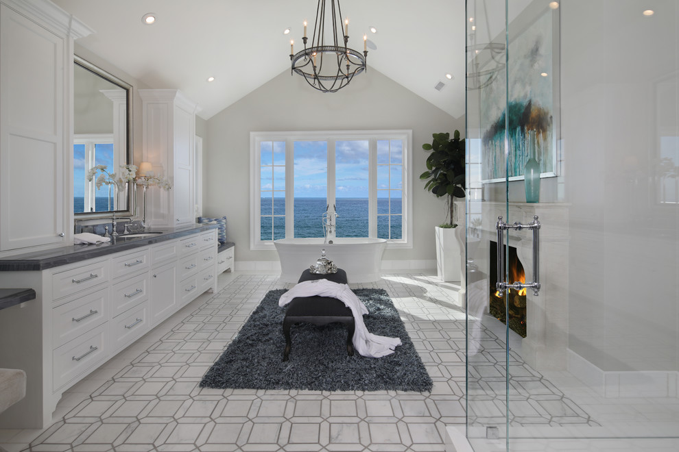 На фото: главная ванная комната в морском стиле с фасадами в стиле шейкер, белыми фасадами, отдельно стоящей ванной, серыми стенами, врезной раковиной и окном с