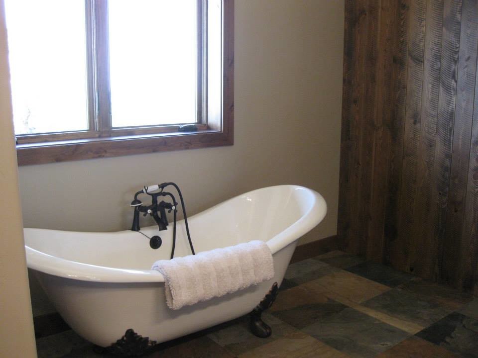 Idée de décoration pour une salle de bain principale chalet de taille moyenne avec une baignoire sur pieds et un sol en ardoise.