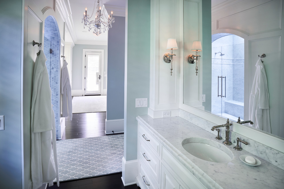 Immagine di un'ampia stanza da bagno padronale minimal con ante con riquadro incassato, ante bianche, doccia doppia, WC monopezzo, pareti blu, parquet scuro, lavabo da incasso e top in marmo