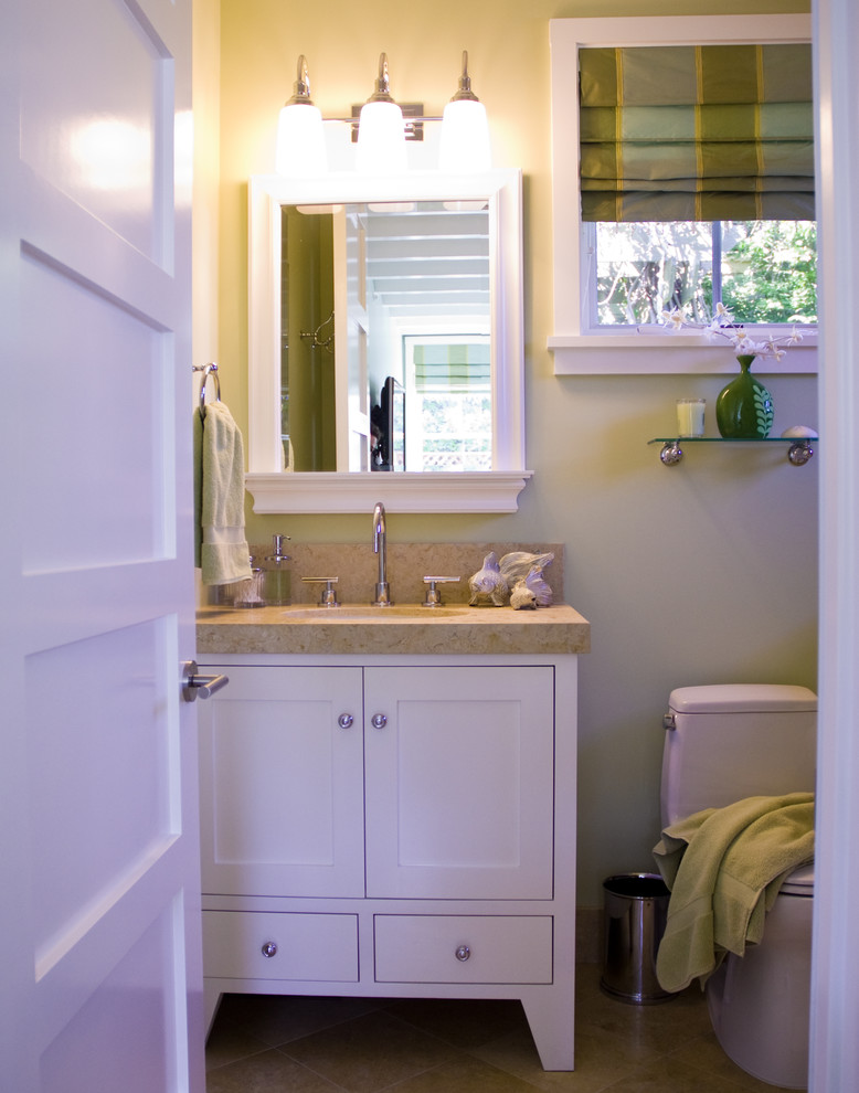 Cette image montre une salle de bain marine avec un lavabo intégré, un placard à porte shaker, des portes de placard blanches, un plan de toilette en calcaire et WC à poser.