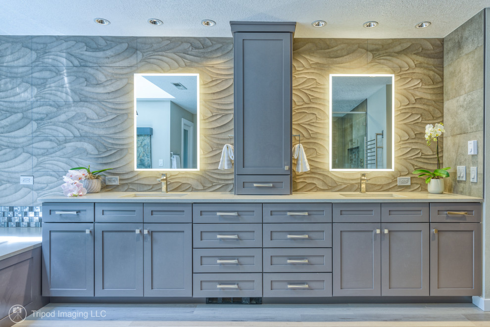 Huge transitional master gray tile and porcelain tile vinyl floor, gray floor and double-sink bathroom photo in Portland with shaker cabinets, a built-in vanity, brown cabinets, a two-piece toilet, gray walls, an undermount sink, quartzite countertops, a hinged shower door and gray countertops