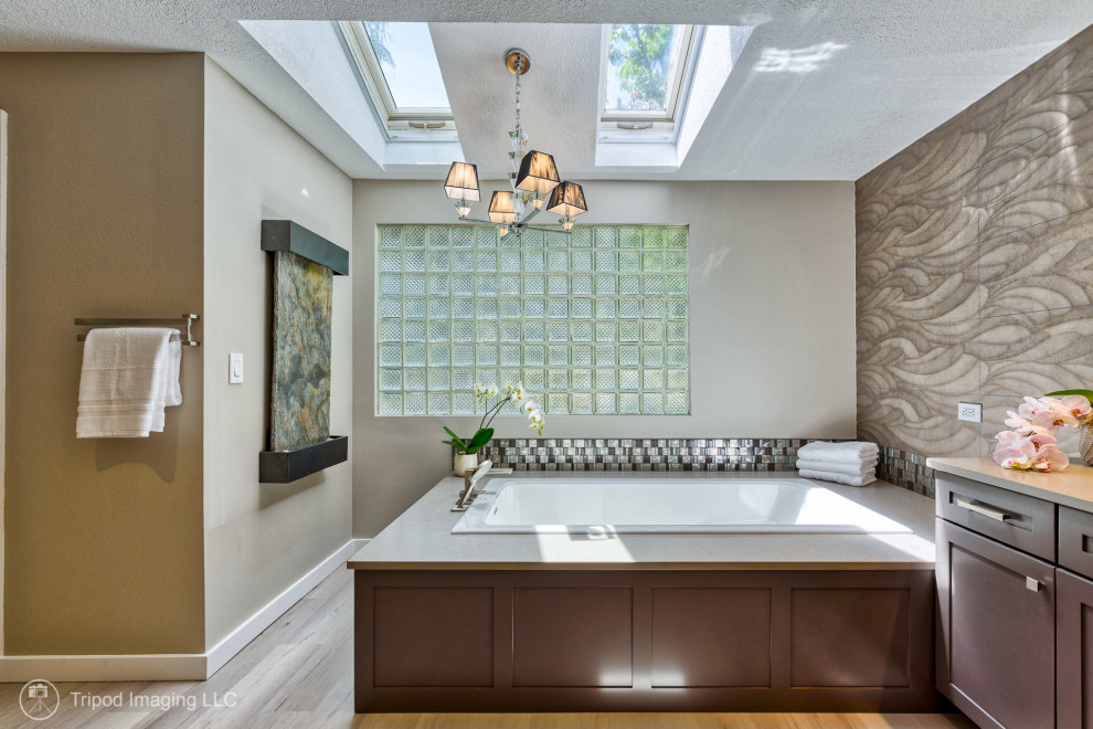 Пример оригинального дизайна: огромная главная, серо-белая ванная комната в стиле неоклассика (современная классика) с фасадами в стиле шейкер, коричневыми фасадами, накладной ванной, угловым душем, раздельным унитазом, серой плиткой, керамогранитной плиткой, серыми стенами, полом из винила, врезной раковиной, столешницей из кварцита, серым полом, душем с распашными дверями, серой столешницей, фартуком, тумбой под две раковины, встроенной тумбой, любым потолком и любой отделкой стен