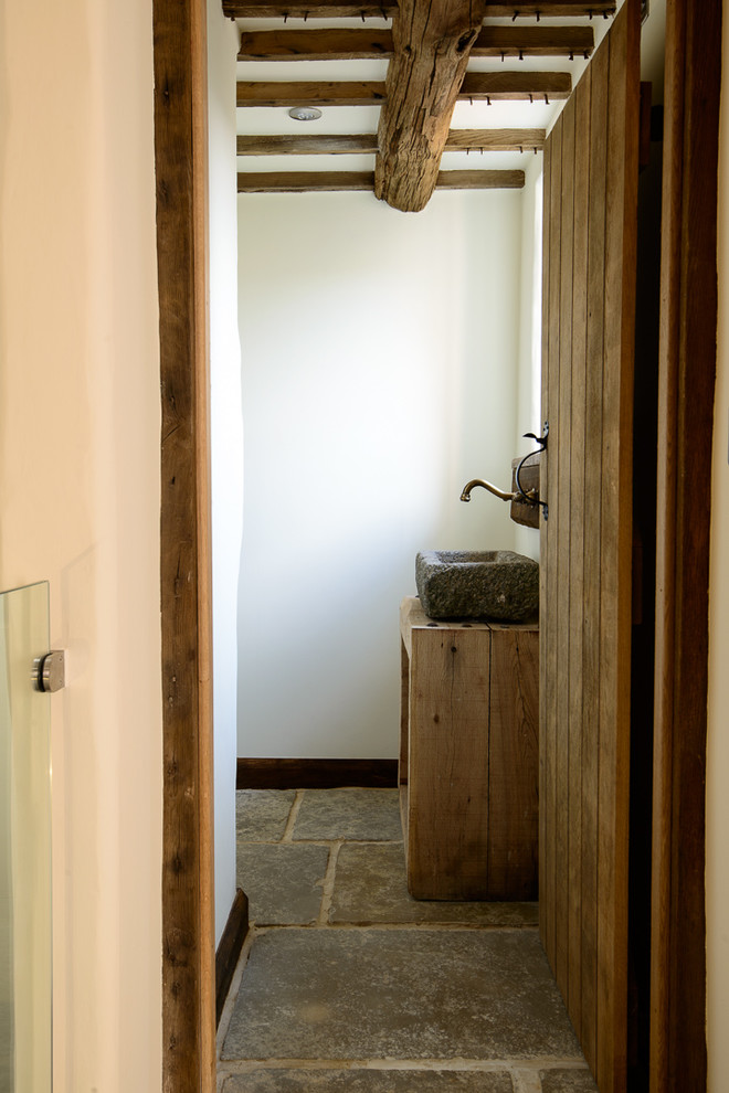 Exemple d'une petite salle de bain montagne en bois brun avec un carrelage gris, des dalles de pierre, un mur blanc, un sol en calcaire, un lavabo de ferme et un plan de toilette en bois.