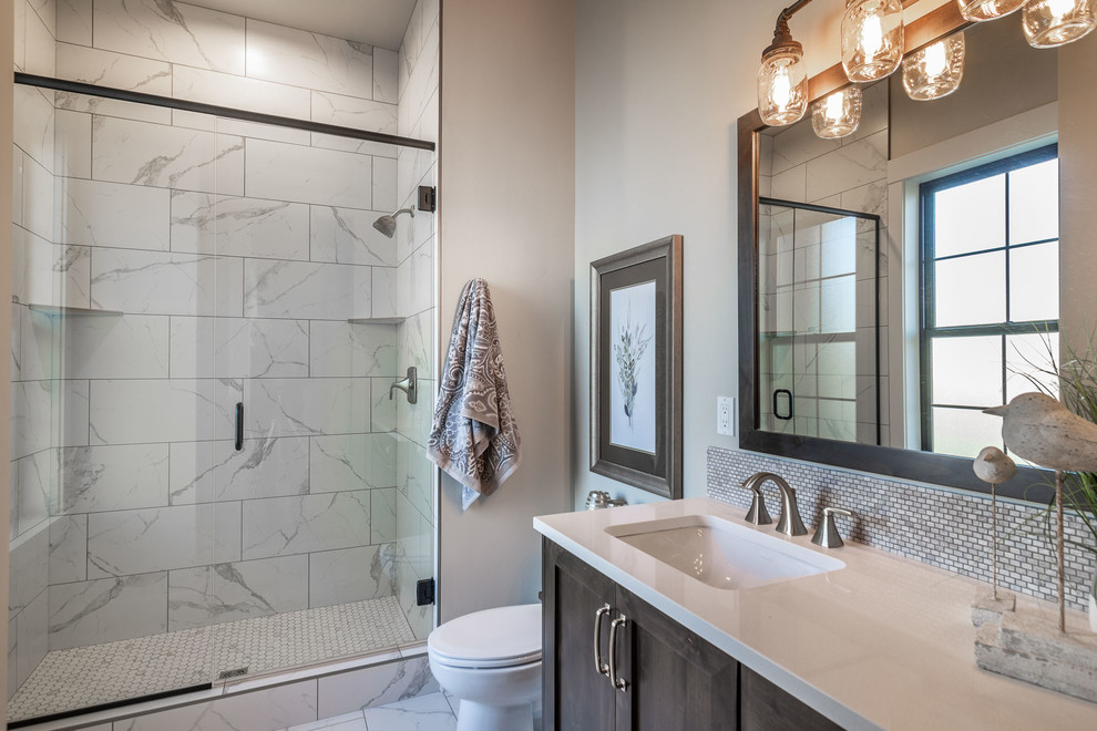 Cette image montre une salle de bain rustique avec un placard à porte shaker, des portes de placard marrons, un carrelage beige, un carrelage gris, un mur gris, un lavabo encastré, un sol blanc, une cabine de douche à porte coulissante et un plan de toilette blanc.
