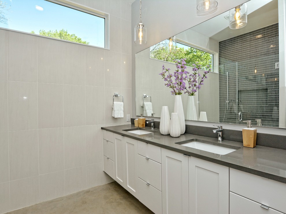 Inspiration for a mid-sized contemporary master white tile and glass tile concrete floor and brown floor double shower remodel in Austin with recessed-panel cabinets, white cabinets, gray walls, an undermount sink, a two-piece toilet, quartz countertops and a hinged shower door