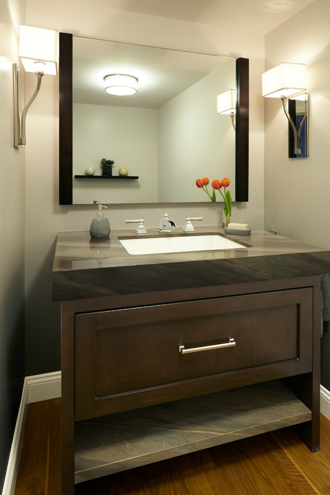 Small trendy medium tone wood floor corner shower photo in Los Angeles with an undermount sink, recessed-panel cabinets, dark wood cabinets, marble countertops, an undermount tub, a one-piece toilet and beige walls