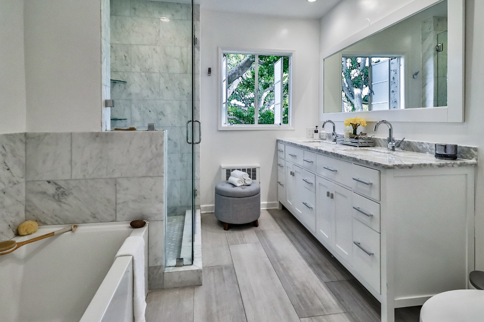 Design ideas for a medium sized rural ensuite bathroom in Los Angeles with shaker cabinets, white cabinets, a built-in bath, a walk-in shower, a one-piece toilet, grey tiles, marble tiles, white walls, porcelain flooring, a built-in sink, marble worktops, grey floors, a hinged door and white worktops.