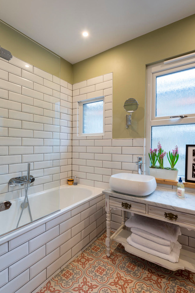 Exempel på ett eklektiskt grå grått badrum med dusch, med skåp i slitet trä, ett badkar i en alkov, en dusch/badkar-kombination, vit kakel, tunnelbanekakel, gröna väggar, ett fristående handfat, marmorbänkskiva, flerfärgat golv, med dusch som är öppen och släta luckor