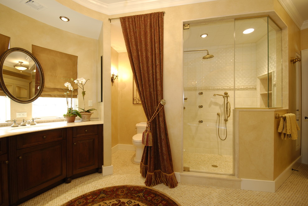Exempel på ett mellanstort medelhavsstil en-suite badrum, med ett undermonterad handfat, luckor med upphöjd panel, skåp i mörkt trä, bänkskiva i kalksten, ett fristående badkar, en toalettstol med separat cisternkåpa, beige kakel, porslinskakel, gula väggar, mosaikgolv och en dusch i en alkov