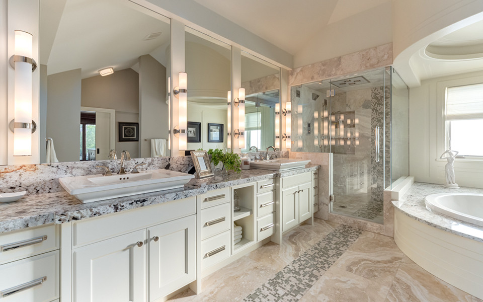 Design ideas for a large traditional ensuite bathroom in Calgary with a vessel sink, recessed-panel cabinets, white cabinets, granite worktops, a built-in bath, a corner shower, beige tiles, porcelain tiles and travertine flooring.
