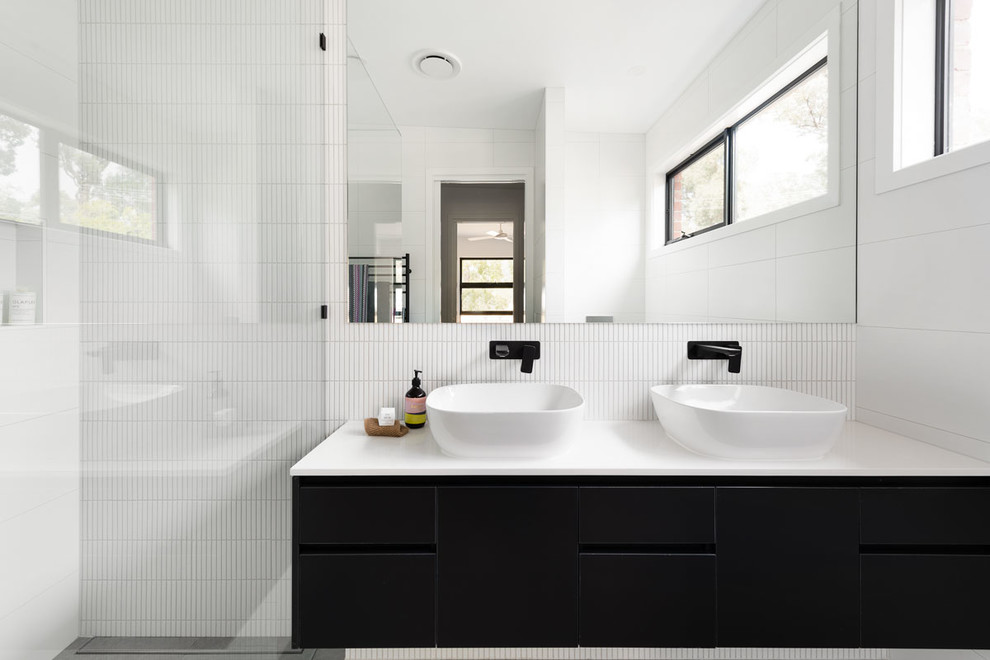 Пример оригинального дизайна: ванная комната в стиле модернизм с черными фасадами, белой плиткой, удлиненной плиткой, белыми стенами, полом из керамической плитки, настольной раковиной, столешницей из искусственного кварца, серым полом, белой столешницей и фасадами островного типа