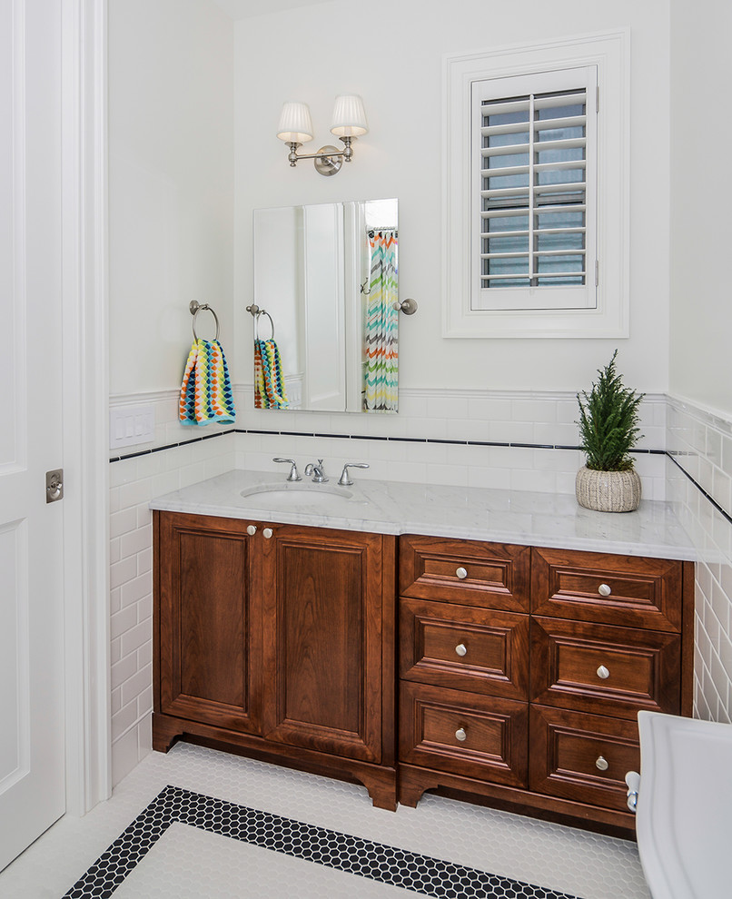 Cette image montre une salle de bain traditionnelle en bois foncé avec un placard avec porte à panneau encastré, un plan de toilette en marbre, un sol en carrelage de terre cuite, un lavabo encastré, un carrelage blanc, un carrelage métro et un mur blanc.