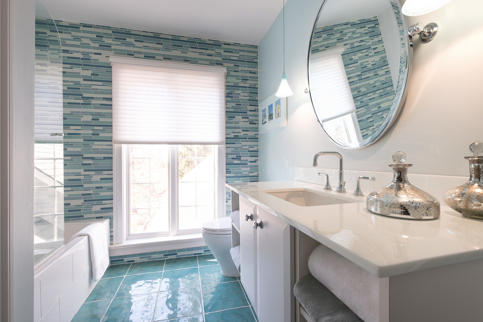 ニューヨークにある中くらいなビーチスタイルのおしゃれなバスルーム (浴槽なし) (フラットパネル扉のキャビネット、白いキャビネット、アルコーブ型浴槽、シャワー付き浴槽	、青いタイル、マルチカラーのタイル、ボーダータイル、白い壁、磁器タイルの床、アンダーカウンター洗面器、人工大理石カウンター、青い床、オープンシャワー、白い洗面カウンター) の写真
