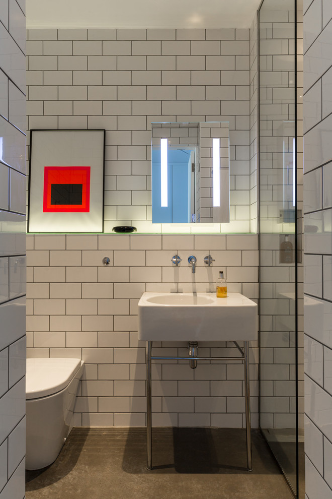 Пример оригинального дизайна: маленькая ванная комната в стиле модернизм с душевой кабиной, открытым душем, унитазом-моноблоком, белой плиткой, бетонным полом, консольной раковиной, стеклянной столешницей, серым полом, открытым душем и плиткой кабанчик для на участке и в саду