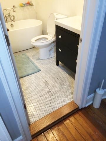 Cette image montre une salle de bain traditionnelle de taille moyenne pour enfant avec des portes de placard noires, une baignoire indépendante, WC à poser, un carrelage gris, des carreaux de céramique, un mur blanc, un sol en carrelage de céramique, un lavabo encastré et un plan de toilette en granite.