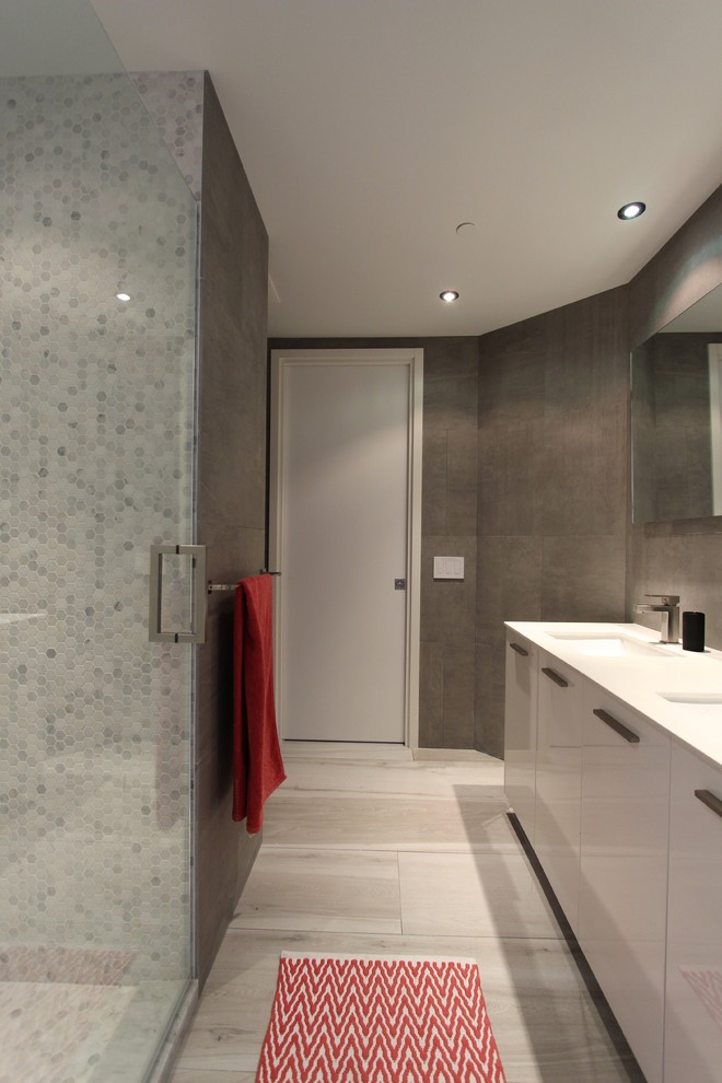 Ispirazione per una stanza da bagno con doccia minimalista di medie dimensioni con ante lisce, ante bianche, doccia alcova, piastrelle grigie, lavabo sottopiano e pareti grigie