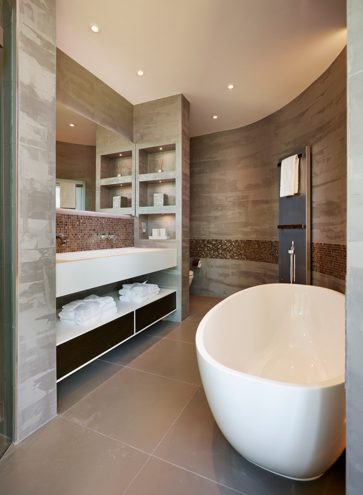Imagen de cuarto de baño principal contemporáneo con armarios con paneles lisos, bañera exenta, baldosas y/o azulejos en mosaico y lavabo integrado