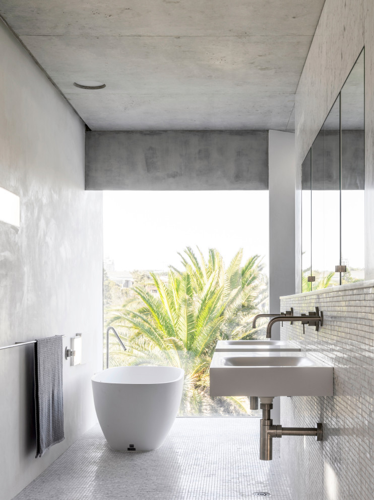 シドニーにあるインダストリアルスタイルのおしゃれな浴室 (置き型浴槽、白いタイル、モザイクタイル、白い壁、モザイクタイル、壁付け型シンク、白い床) の写真