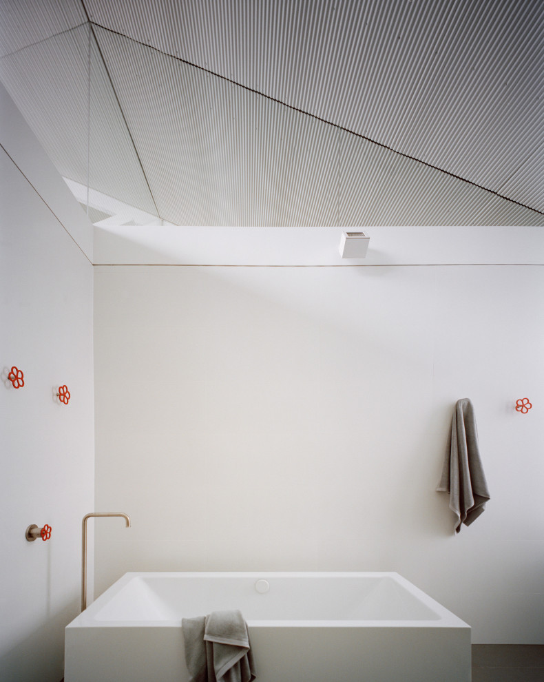 На фото: ванная комната в стиле лофт с отдельно стоящей ванной, белыми стенами и сводчатым потолком с