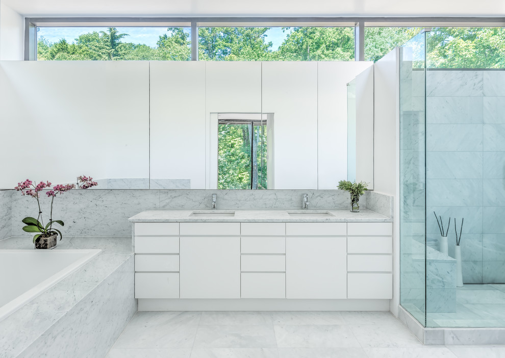 На фото: ванная комната в современном стиле с врезной раковиной, мраморной столешницей, накладной ванной, двойным душем, белой плиткой, каменной плиткой, белыми стенами, мраморным полом, плоскими фасадами и белыми фасадами