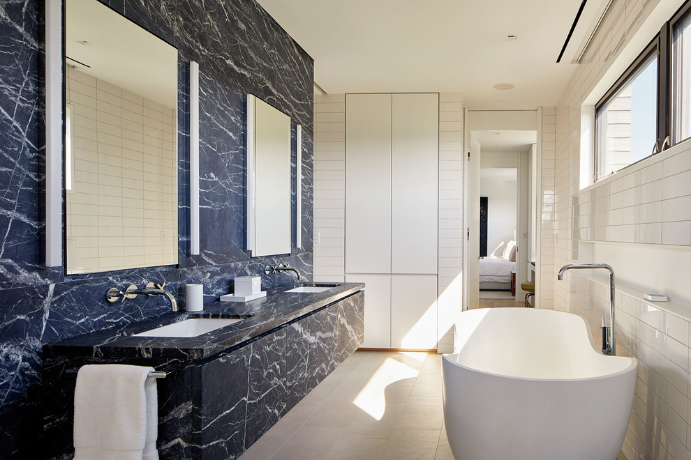 Photo of an expansive nautical ensuite bathroom in New York with a freestanding bath, blue tiles, white tiles, white walls, a submerged sink, beige floors and blue worktops.