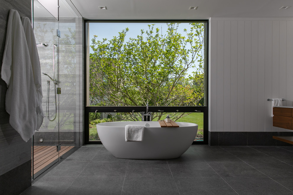 Exempel på ett stort modernt grå grått en-suite badrum, med släta luckor, skåp i mellenmörkt trä, ett fristående badkar, våtrum, grå kakel, travertinkakel, ett undermonterad handfat, bänkskiva i kalksten och dusch med gångjärnsdörr