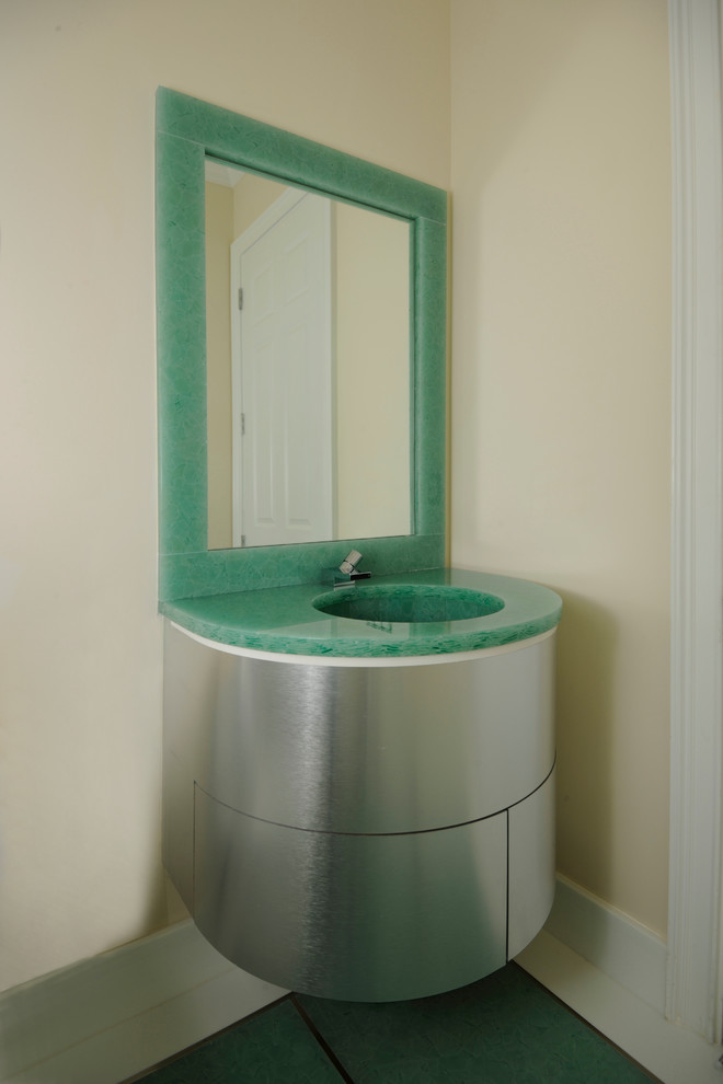 Inredning av ett modernt litet badrum med dusch, med ett integrerad handfat, släta luckor, grå skåp, bänkskiva i glas, en toalettstol med hel cisternkåpa, grön kakel, gula väggar, ett undermonterat badkar, en dusch i en alkov, mosaik, klinkergolv i keramik, vitt golv och dusch med gångjärnsdörr
